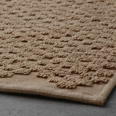 Textured beige bath mat with irregular, soft texture for comfort. Made of cotton for quick drying and high absorption.
