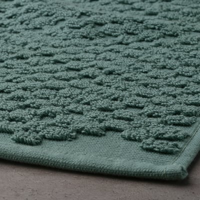 Close-up of soft, turquoise bath mat. Highly textured, terry cotton feels comfy and absorbent.