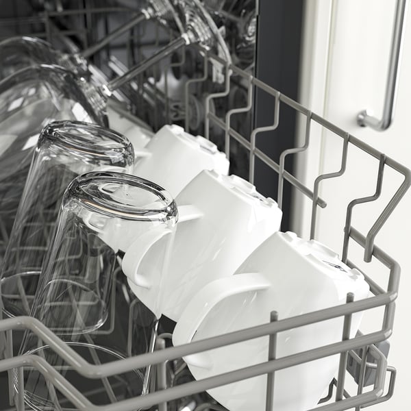 Dishwasher with glasses and cups neatly arranged in racks, ready for washing.