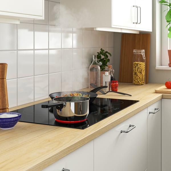 Modern kitchen with FROMMESTA black hob, wooden countertop, and stainless steel cabinets.