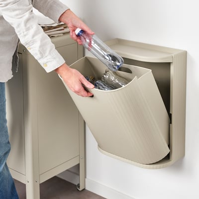 Person recycling plastic bottle into beige GÅRDSBUTIK wall-mounted bin.
