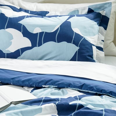 Bed with GETRUTA bedding, featuring soft, floral-patterned comforter and white sheeting. Visiting smooth and inviting.