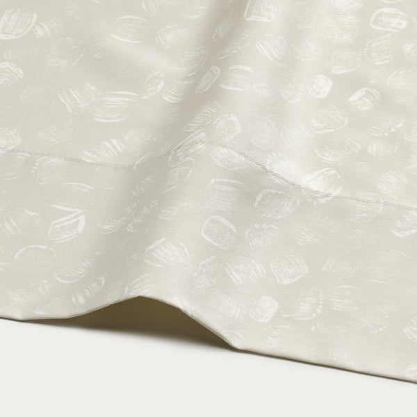 Close-up of luxurious, cream-colored bed sheet with subtle, artistic pattern. Smooth, high-quality fabric.