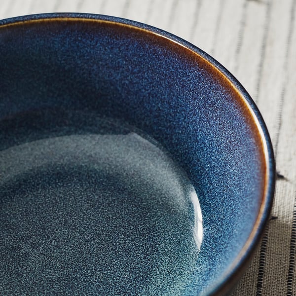 Blue bowl with gold rim on placemat.