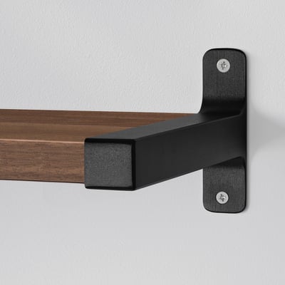 Wall-mounted shelf with black metal brackets securely holding the wooden shelf, showcasing sturdy and modern design.