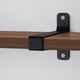 Wooden shelf securely attached to wall with sturdy black metal brackets.