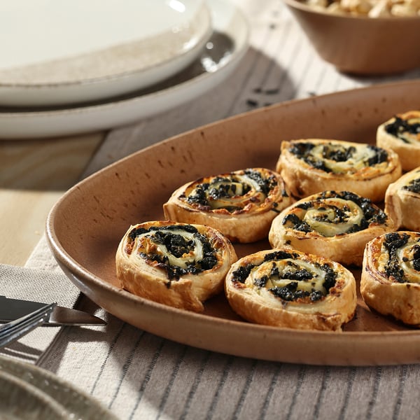 Rustic grey stoneware plate holds eight round spinach tarts, larger than dinner plates.
