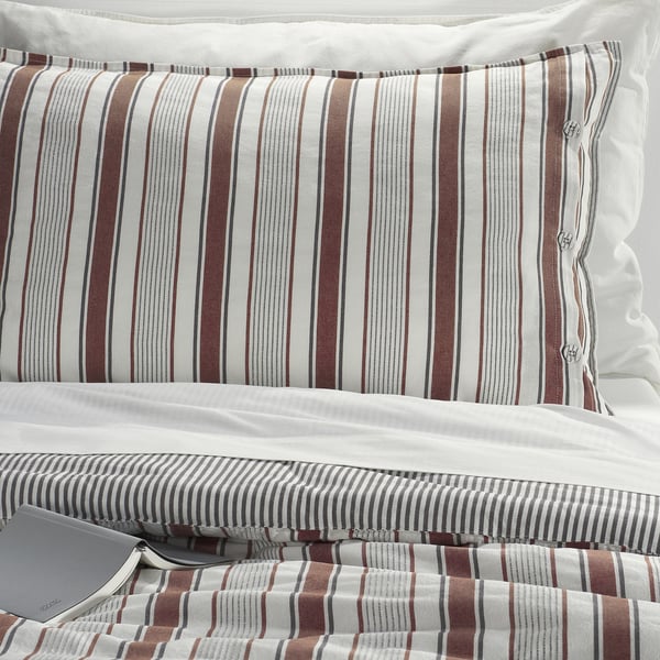 Crisp striped pillow sham with decorative buttons on a cosy, dobby-woven cotton comforter, showcasing high-quality craftsmanship and inviting texture.