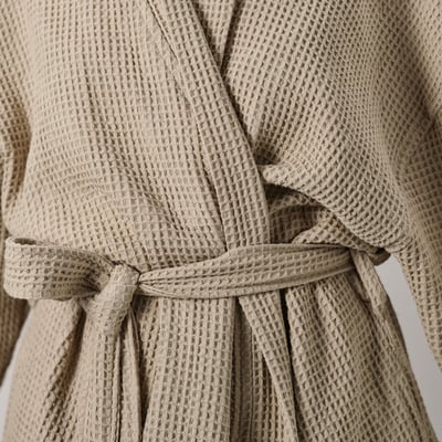 Close-up of soft, beige waffle texture robe tied with a belt.