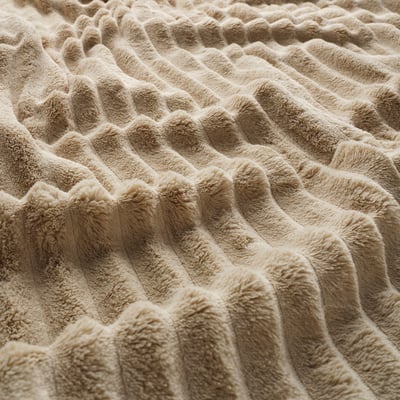 Folded beige blanket with soft, textured patterns close-up.