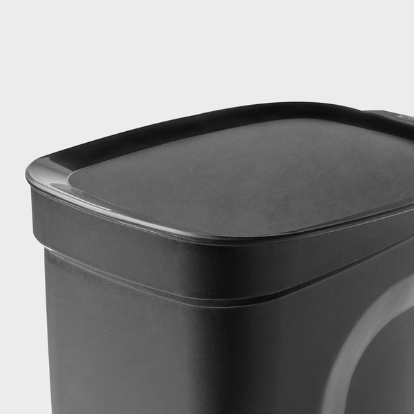 Black plastic pedal bin with sleek, curved edges and handle at back, designed for kitchen use.