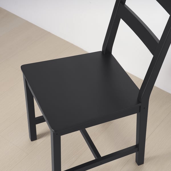 Black wooden chair, sturdy solid pine design. Square seat, slatted back, and sleek legs.