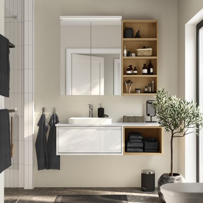 Modern bathroom with light wood hagån cabinet, mirror, towels, and plants.