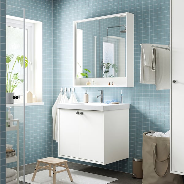 Modern bathroom with light blue tiles, HAVBÄCK sink, stool, towels, and plant.