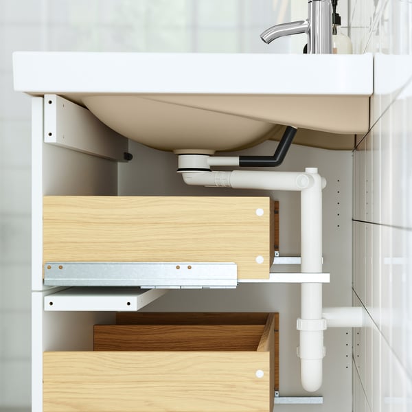 Bathroom vanity with wooden drawers and pipe drainage, shown from underneath.
