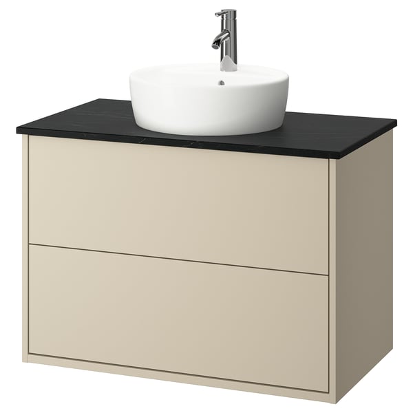A HAVBÄCK beige wall-mounted bathroom cabinet with a black countertop and a round white ceramic basin. It two drawers and a modern design.
