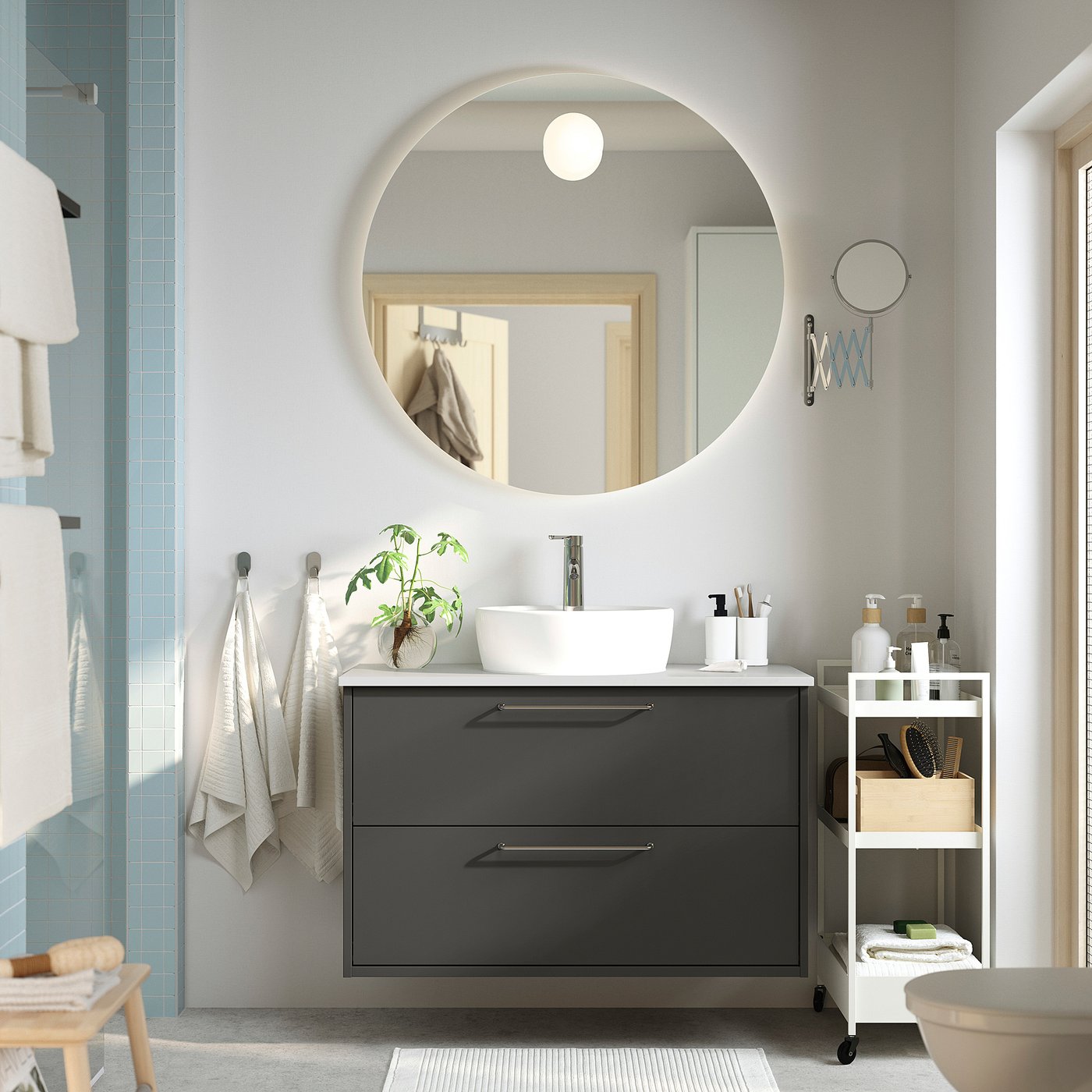 Modern bathroom with dark grey HAVBÄCK vanity, round mirror, white basin, and glass shower.