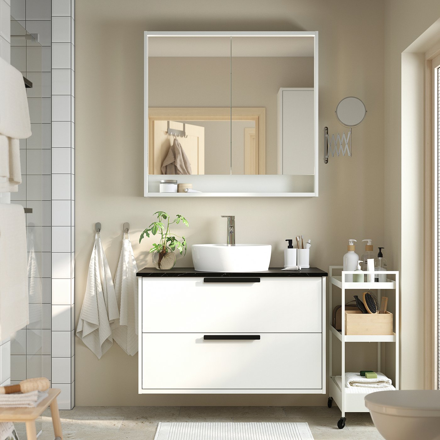 Modern bathroom with white vanity, mirror, & storage. Black handles, towels, & plant. Minimalist.