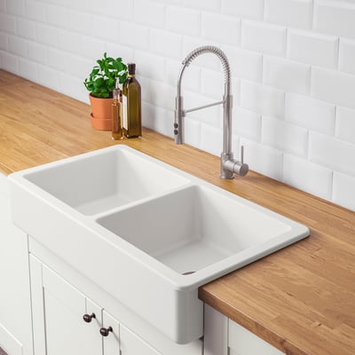 Modern kitchen sink with white ceramic basin, integrated tap, wooden countertop, and plant.