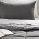 Grey comforter set with pillow on bed, soft brushed fabric, showcasing quality and comfort.