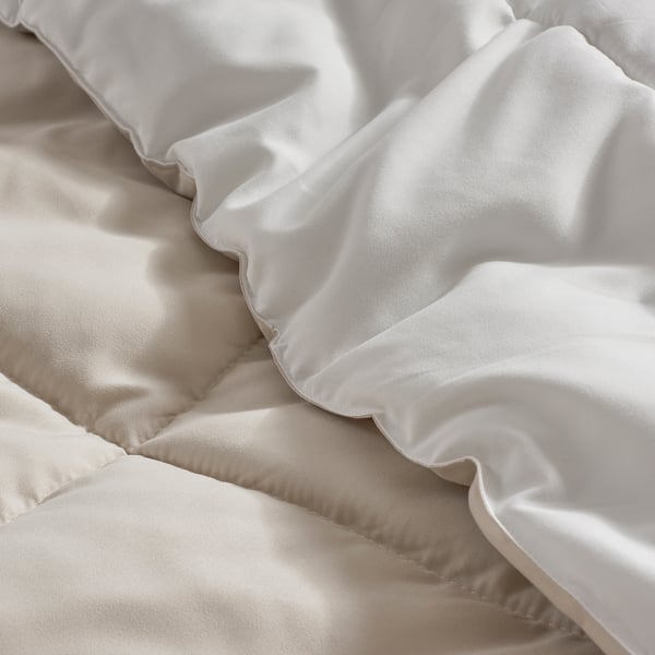 Soft, luxurious comforter with smooth, neatly stitched edges in neutral tones.