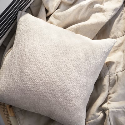 Off-white cotton pillow with textured pattern, rectangular shape, zip closure.