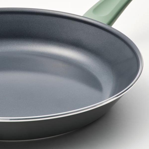 Close-up of a non-stick frying pan with a green handle, showcasing its smooth interior.