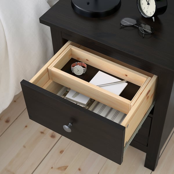 Open wooden drawer revealing a wristwatch, pen, and paper, showcasing organisation of small items.