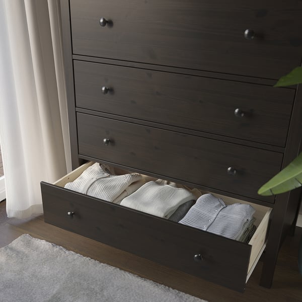 Open wooden dresser with folded clothes in drawers, showing storage and organisation.