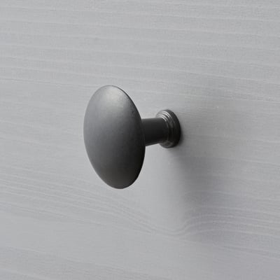 Round, matte black wall-mounted hook, sleek and modern design.