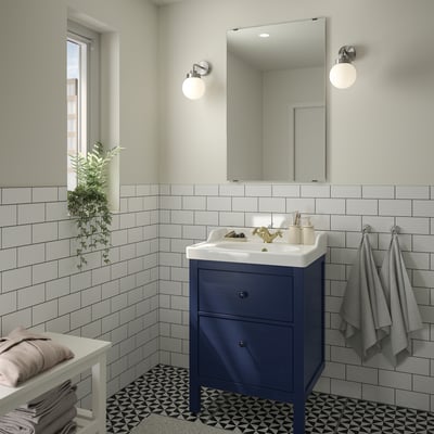 Blue HEMNES vanity, gold fixtures, grey towels, large mirror.