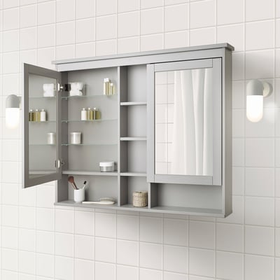 Wall-mounted cabinet with mirror, holding toiletries.