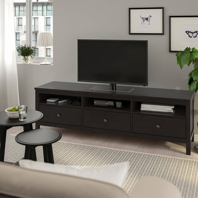 Modern living room with dark wood HEMNES tv stand, flat screen tv, coffee tables, and patterned rug.