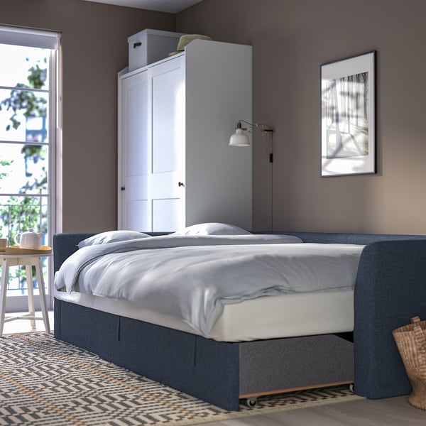 Modern bedroom with sofa-bed, blue upholstery, storage, & minimal decor.