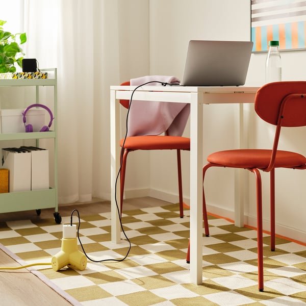 Home office: white desk, orange chair, laptop with yellow extension cord.