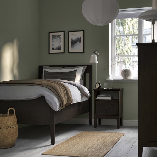 Bedroom with dark brown IDANÄS bed, green wall, large window, basket, bedside table with lamp and clock