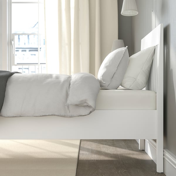 Bedroom with IDANÄS bed, white/gray linens, sunlight streaming in.