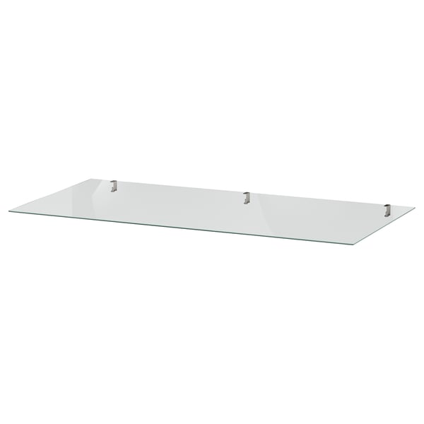 A clear IDANÄS glass shelf, square-shaped, supported by four metal brackets.