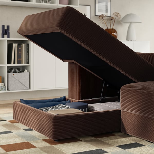 Modern sofa with storage: lifted seat reveals cushions, blankets, and books, showcasing versatile comfort and practical space-saving design.