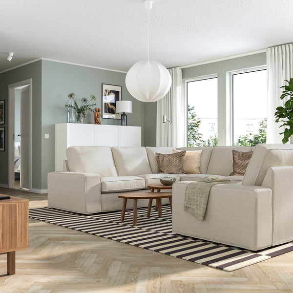 Modern living room with grey KIVIK sofa, black-white rug, pendant lamp, coffee table, and large windows.