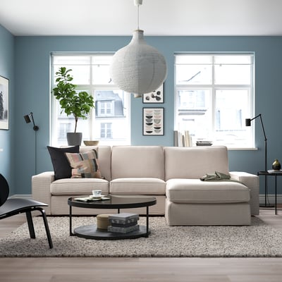 Modern living room with KIVIK sectional sofa in light grey, large windows, and stylish decor.