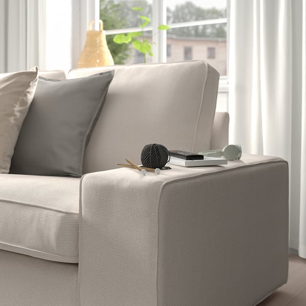 Modern sofa with cosy pillows and armrest decor, near window.