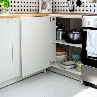 Kitchen cabinet open, showing adjustable shelf for pots, pans, and bowls.
