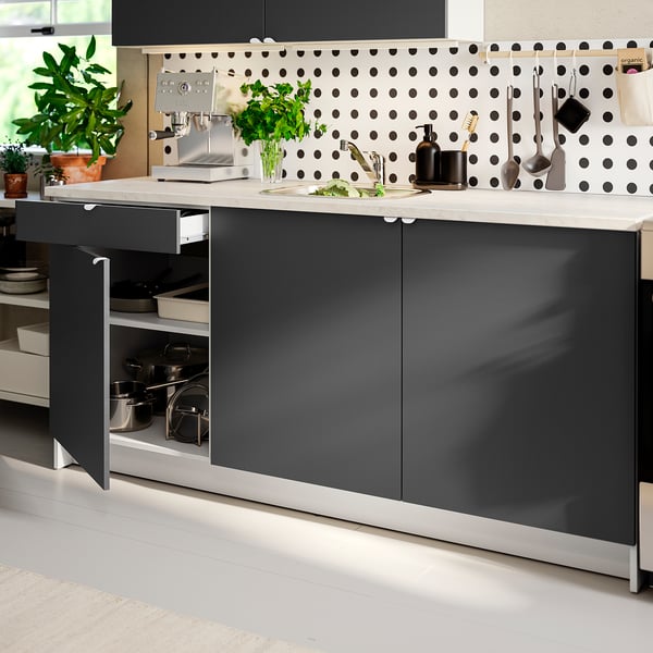 Modern kitchen island with dark grey cabinets, marble counter, and polka dot backsplash. Organised cookware drawer open.