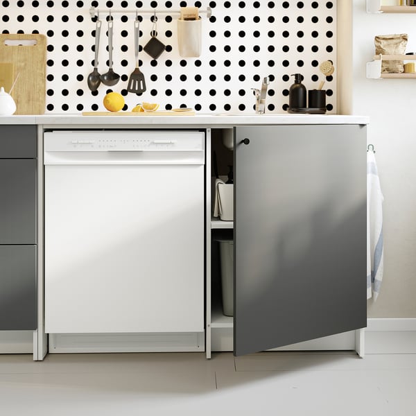 Modern kitchen setup: dishwasher open, utensils hung on pegboard, lemons on counter.