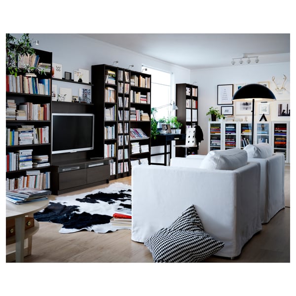 Modern living room with black bookshelves, large tv, white sofa, patterned rug, and decorative pillows.