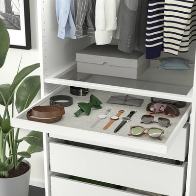 Wardrobe organiser with drawer for accessories, upper shelves with clothes and plant beside.