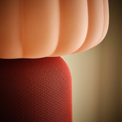 Peach-colored lamp base made of woven red material, with a ribbed glass shade.