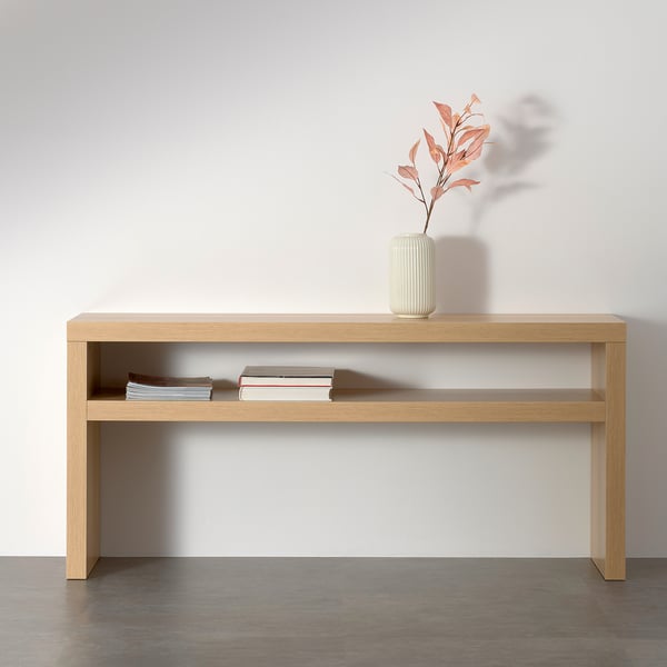 Minimalist console table with open shelf for books, supported by honeycomb-patterned paper, ideal for organising and moving.