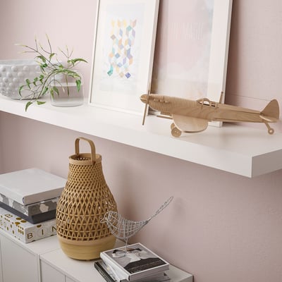 Shelf displays plane model, plant, basket, and books. Minimalist storage items.